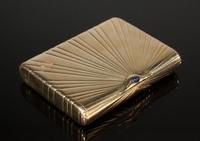 Lot 374: FABERGE 14K YELLOW GOLD AND SAPPHIRE CIGARETTE CASE.  With Russian gold mark for 14k, designed as a rectangular fluted case with cabochon sapphire push-piece, with a signed wooden fitted case.  3 1/2 by 2 3/4 by 1/2 inches, 187 gms.