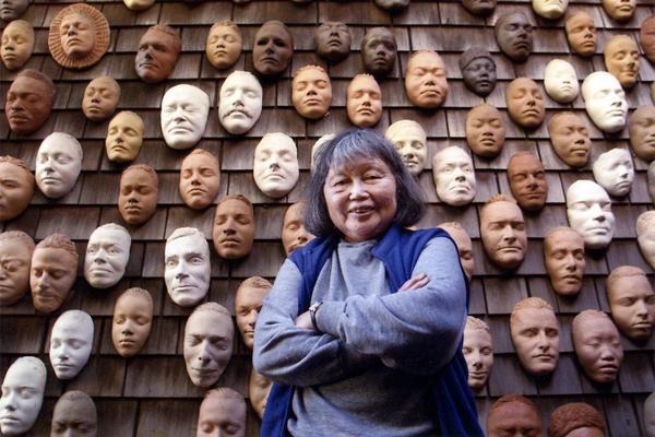 Ruth Asawa with life masks on the exterior wall of her house.  (Image credit: Photography by Terry Schmitt.  ARTWORK: Untitled (Wall of Masks), c.  1966–2000.  Ceramic, bisque-fired clay.  © 2020 Estate of Ruth Asawa/ Artists Rights Society (ARS), New York.  Courtesy The Estate of Ruth Asawa and David Zwirner)