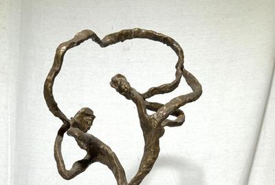 This abstract figural bronze sculpture ($400-600), signed Estelle Goodman, of a man and a woman, with their backs to one another yet connected by a figurative representation of communication in the form of a flowing ribbon between their mouths.  It stands 18¼ inches tall.