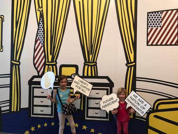 Visitors engage with props in the "Oval Office" at the entrance of the Skirball Cultural Center's exhibition "Pop for the People: Roy Lichtenstein in L.A."