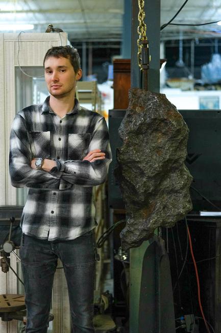 Gallery 63 owner Elijah Brown stands alongside the massive, museum-quality meteorite that will be sold online Tuesday, April 6th, at 11 am Eastern time.  The stand measures 74 inches tall.