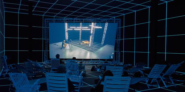 Hito Steyerl, "Factory of the Sun," 2015.  Single channel high definition video, environment, luminescent LED grid, beach chairs, 23 minutes.  Installation view from the Venice Biennale, German Pavilion, 2015.  Image courtesy of the Artist, Andrew Kreps Gallery, New York and Esther Schipper, Berlin.  Photography by Manuel Reinartz.