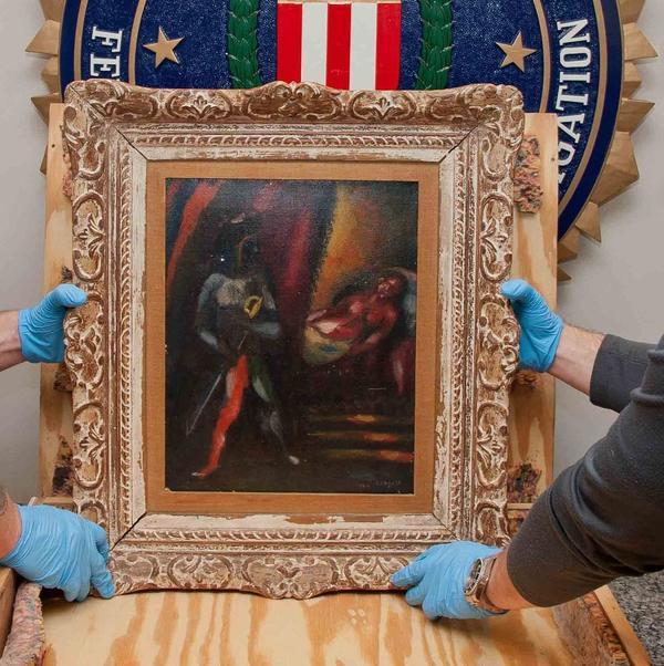 Personnel from the FBI’s Art Crime Team hold a framed work by Marc Chagall prior to its return to the owners’ estate nearly 30 years after it was stolen.