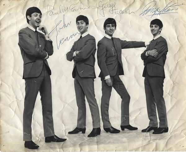 Vintage 8 inch by 10 inch photograph, featuring the Fab Four in their iconic, collarless suits, signed by all four Beatles – John, Paul, George and Ringo – in 1963, in blue ballpoint ink.