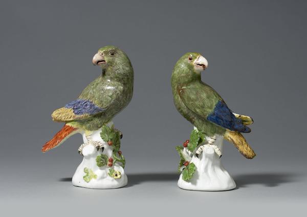 An Important Pair of Early Meissen models of South American Parrots, modelled by Johann Joachim Käendler each perched upon a white tree stump and looking to one side, beautifully naturalistically coloured, each representing a Green Amazon Parrot painted in green with puce detailing to its plumage, and with red, blue and yellow wing tips and tail, the tree stumps issuing leafy berried branches.  Circa 1738-42 1st height: 7 ¾ in (19 ½ cms)2nd height: 7 ½ ins (19 cms) 