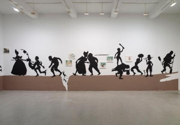 Kara Walker The Nigger Huck Finn Pursues Happiness Beyond the Narrow Constraints of your Overdetermined Thesis on Freedom — Drawn and Quartered by Mister Kara Walkerberry, with Condolences to The Authors, 2010 Cut paper and paint on wall and gouache and ink on paper.  Approximately 57 feet.