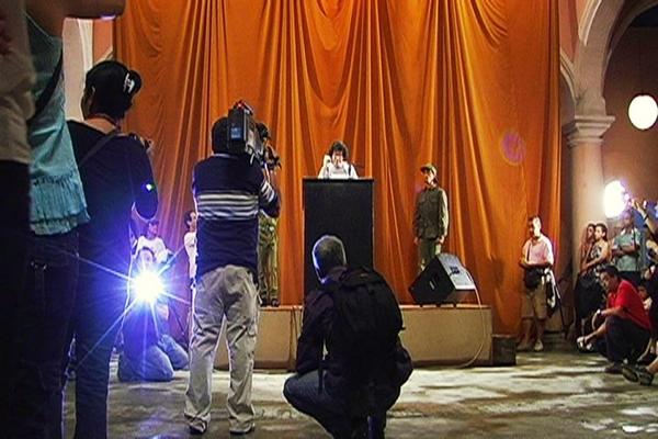 Tatlin’s Whisper, #6 (Havana Version), 2009 Stage, podium, microphone, loudspeakers, curtain, two people dressed in military fatigues, dove, audience, and 200 disposable cameras Wifredo Lam Center, Havana 