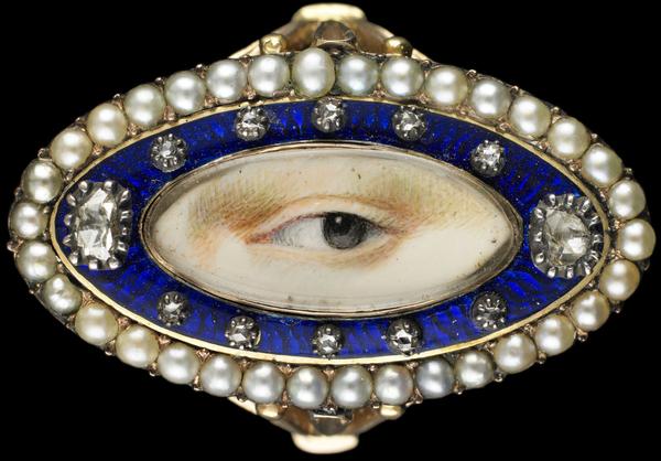 Rose gold oval ring surrounded by a blue enamel border containing ten small and two large diamonds enclosed in a border of natural split pearls, ca.  1790.  Brown left eye.  Purchased from Edith Weber, New York.  Dimensions: 3⁄4 × 1 1⁄4 × 7⁄8 in.