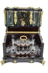 19th century French Napoleon III tantalus or cave a liqueur (either way, a decanter set), in an ebonized wood oxbow cabinet having four decanters and sixteen glasses (est.  $1,000-$2,000).