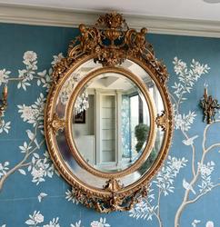 Large 19th century Louis XVI style giltwood mirror from the Beaux Arts period, having a crest and pendant with urn, putti and floral swags, a divided oval frame with cabochon cartouches.