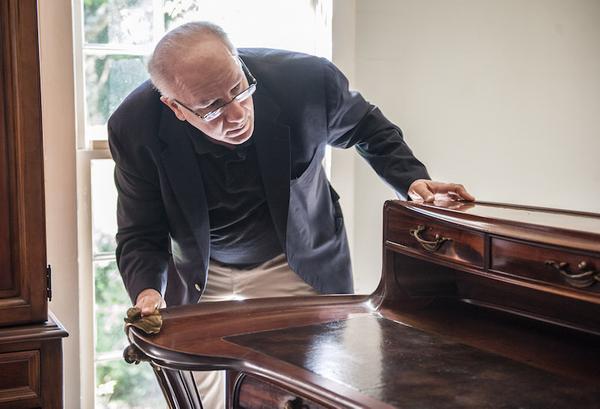 Mr.  Goldberg inspecting characteristics of furniture for appraisal.