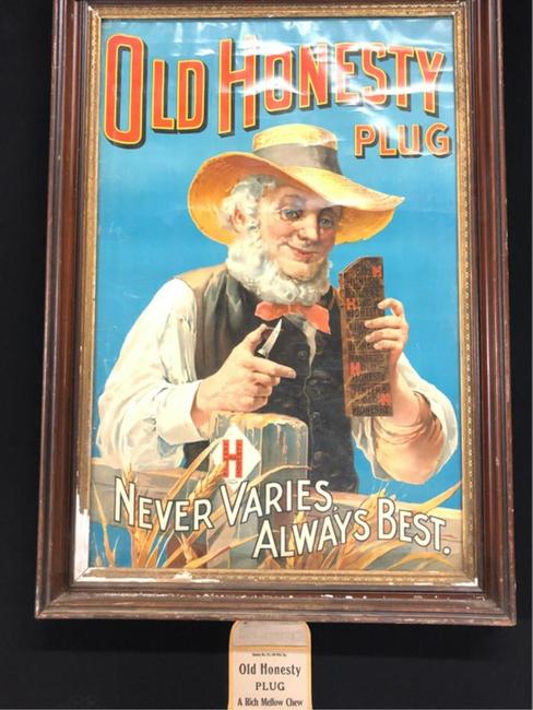 Framed advertising poster for Old Honesty plug tobacco (“Never Varies, Always the Best”), depicting a bearded man cutting off a piece of plug, plus a plug tobacco bag (est.  $100-$200).