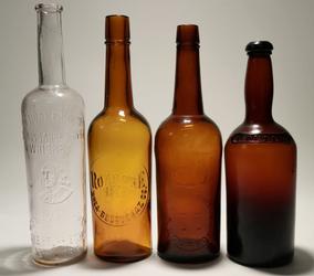 Set of four 1800s bourbon and whiskey bottles, including a rare J.  Moore Brown Old Bourbon, a Roanoke Rye brown, a blob top brown and a clear Old Quaker Club Whiskey (est.  $350-$1,000).