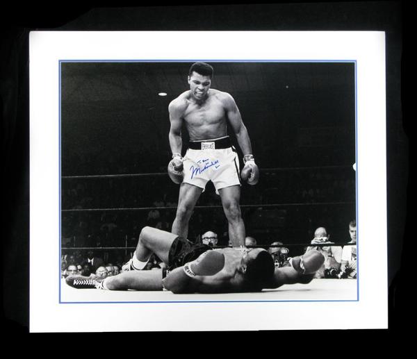 Huge black and white photo of Muhammed Ali, shown glowering over Sonny Liston, signed by Ali using a blue Sharpie and double matted in a 35 inch by 29 ½ inch frame (est.  $800-$1,000).