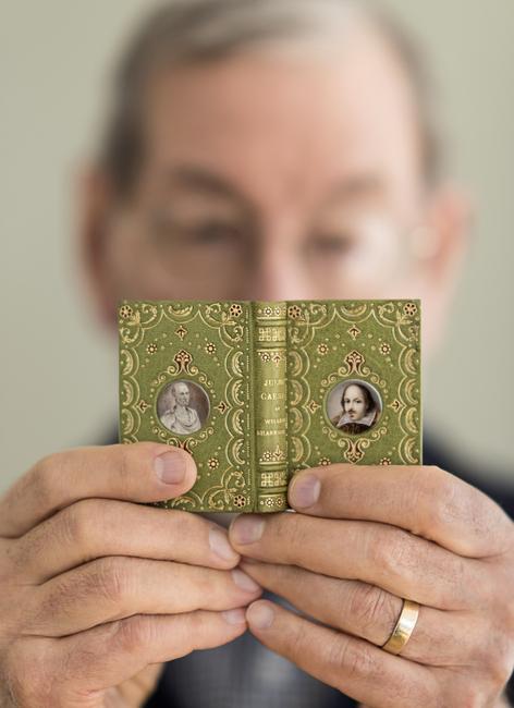 Neale Albert holding 3" book “Julius Caesar” bound by Santiago Brugalla, 2004, one of the volumes of the Knickerbocker set of Shakespeare.  Bound in green goatskin, with gold and red tooling.  Miniature portrait medallions, painted by John Hodgson, on front and back covers in imitation of a Cosway-style binding.  