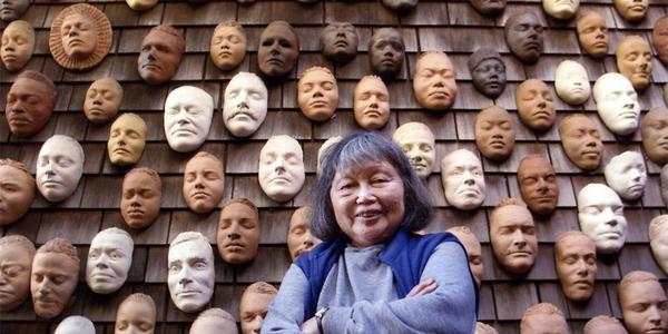 Ruth Asawa with life masks on the exterior wall of her house.  (Image credit: Photography by Terry Schmitt.  ARTWORK: Untitled (Wall of Masks), c.  1966–2000.  Ceramic, bisque-fired clay.  © 2020 Estate of Ruth Asawa/ Artists Rights Society (ARS), New York.  Courtesy The Estate of Ruth Asawa and David Zwirner)