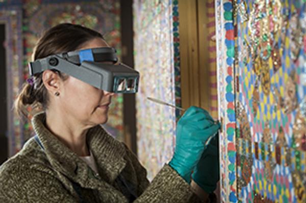 Conservator Cricket Harbeck working in the Preservation Lab: Loy Bowlin's Holy Jewel Home at the John Michael Kohler Arts Center, 2016.