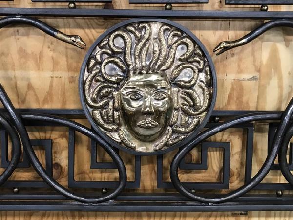 A custom made Versace bed frame replica ($5/10,000) made by an artisan metalworker in Maine is crafted from iron, bronze and brass.  It features an exact detailing of a Medusa head, framing snakes, Greek key design and originally cost $40,000; 70 by 82 inches.  