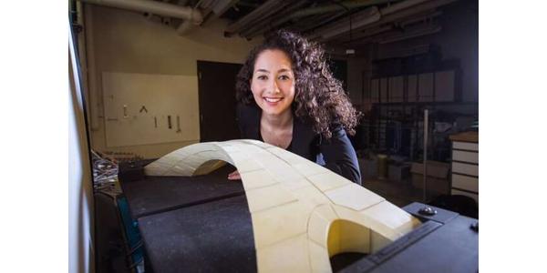 Masters of engineering student Karly Bast of MIT shows off the scale model of a bridge designed by Leonardo da Vinci that she and her co-workers used to prove the design’s feasibility.  Credit: Gretchen Ertl