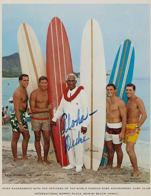 KAHANAMOKU, DUKE PAOA.  Photolithograph Signed ("Aloha - Duke"), 1960s, showing The Duke with the Officers of his Surf Club on Waikiki Beach.  This image was used for a Pan Am promotional flyer.  Estimate: $1,500 - 2,500 