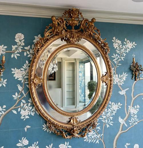 Large 19th century Louis XVI style giltwood mirror from the Beaux Arts period, having a crest and pendant with urn, putti and floral swags, a divided oval frame with cabochon cartouches.